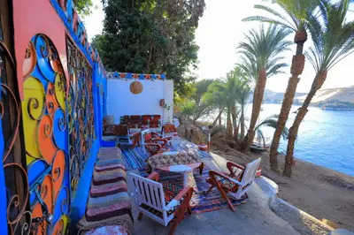 a group of chairs and tables next to the water at Nubian studio in Aswan