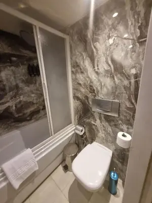 a bathroom with a white toilet and a marble wall at Nile Cruise 3 & 4 & 7 Nights in Luxor