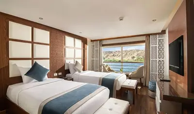 a hotel room with two beds and a television at Nile Cruise 3 & 4 & 7 Nights in Luxor