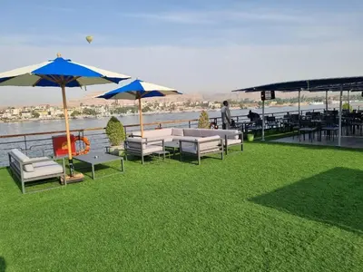 a patio with chairs and umbrellas on the grass at Nile Cruise 3 & 4 & 7 Nights in Luxor