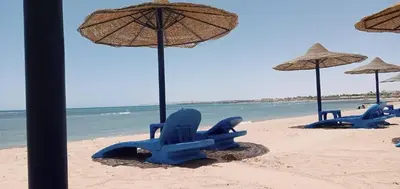 a group of blue beach chairs and umbrellas on a beach at Schöne Ferienwohnung in Cecelia Resort, am Pool und wunderschönen Strand für Familien und Paare in Hurghada