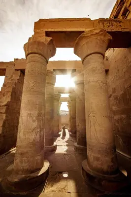 a group of columns in a building with the sun in the background at Nile Treasure Cruise - 4 or 7 Nights From Luxor each Saturday and 3 or 7 Nights From Aswan each Wednesday in Luxor