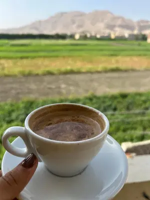 a person holding a cup of coffee with a view at sun smile guest house᭄ꦿ in Luxor
