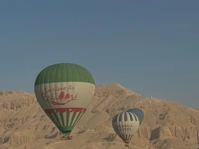 two hot air balloons flying in the desert at sun smile guest house᭄ꦿ in Luxor