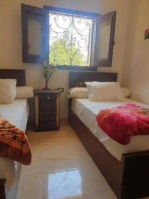 a bedroom with two beds and a window at النبلاء جيست هاوس نوبيان اسوان in Aswan