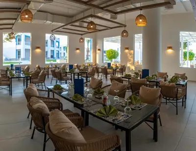 a dining room with tables and chairs and windows at Casa Blue Resort in Marsa Alam City