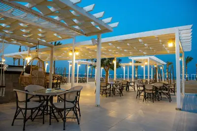 a patio with tables and chairs on the beach at night at Casa Blue Resort in Marsa Alam City