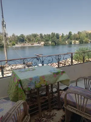 a table and chairs on a balcony with a view of a river at Nubian Bride guest house in Aswan