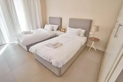 two beds with white sheets in a room at Ground floor two bedrooms in Joubal Lagoon with direct pool access and view in Hurghada