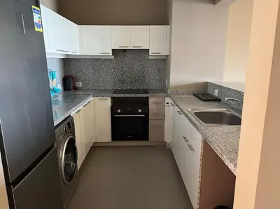 a small kitchen with white cabinets and a dishwasher at Ground floor two bedrooms in Joubal Lagoon with direct pool access and view in Hurghada