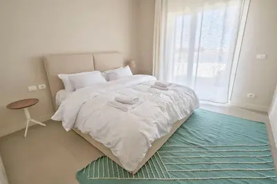 a white bedroom with a large bed and a window at Ground floor two bedrooms in Joubal Lagoon with direct pool access and view in Hurghada