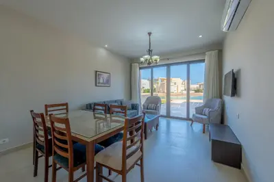 a dining room and living room with a table and chairs at Brand-New Family House in Tawila El Gouna Lagoon and Pool Access in Hurghada