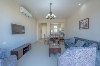 a living room with blue couches and a dining room at Brand-New Family House in Tawila El Gouna Lagoon and Pool Access in Hurghada