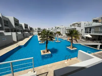 a large swimming pool with palm trees in a building at Ground floor one bedroom overlooking the pool. in Hurghada