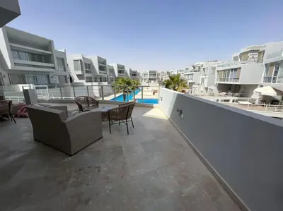 a balcony with a table and chairs on a building at Ground floor one bedroom overlooking the pool. in Hurghada