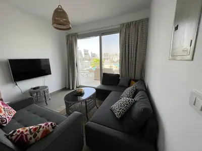 a living room with two couches and a television at Ground floor one bedroom overlooking the pool. in Hurghada