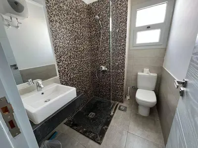 a bathroom with a toilet and a sink and a shower at Ground floor one bedroom overlooking the pool. in Hurghada