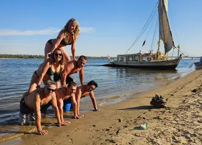 a group of people on the beach with a boat at Nile Felucca Adventure in Aswan