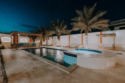 a swimming pool with palm trees and a building at Luxury private villa with pool in Hurghada
