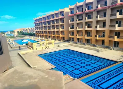 a hotel with a swimming pool in front of a building at Selena Bay Luxury Resort - Premium Apartment with Private Beach in Hurghada