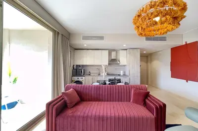 a living room with a pink couch and a kitchen at Snazzy 1BDR w Rooftop Mangroovy Free Pool & Beach Access in Hurghada