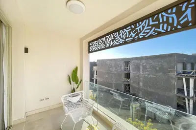 a balcony with a large window with a white chair at Snazzy 1BDR w Rooftop Mangroovy Free Pool & Beach Access in Hurghada