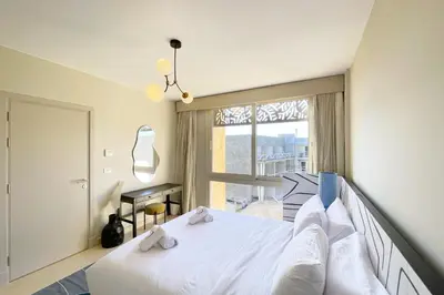 a bedroom with a white bed and a window at Snazzy 1BDR w Rooftop Mangroovy Free Pool & Beach Access in Hurghada