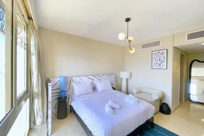 a bedroom with a bed with white sheets and pillows at Snazzy 1BDR w Rooftop Mangroovy Free Pool & Beach Access in Hurghada