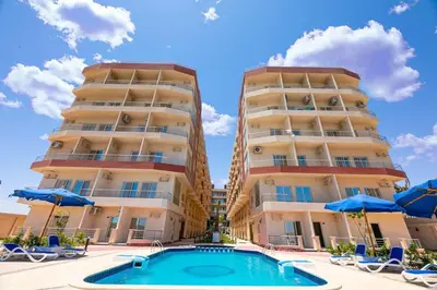 a hotel with a swimming pool in front of two tall buildings at Casablanca beach resort, first line with private beach and swimming pools, in Hurghada