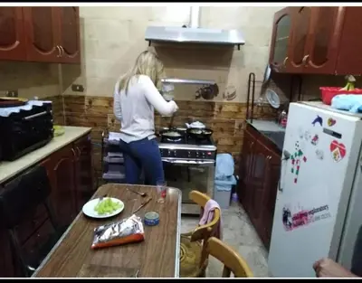 a woman standing in a kitchen cooking in a stove at NUBA ONe in Aswan