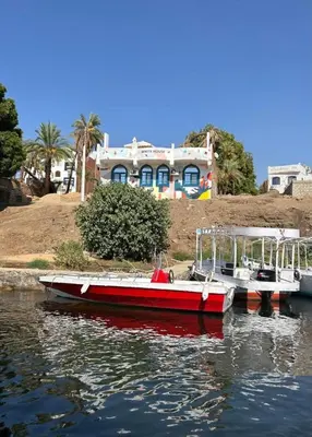 two boats docked in the water in front of a house at White House in Aswan