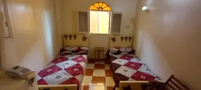 two beds in a small room with a window at Gasser Holiday Home in Aswan