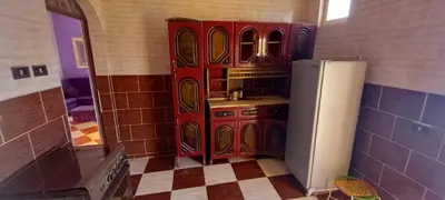 a kitchen with red cabinets and a refrigerator at Gasser Holiday Home in Aswan