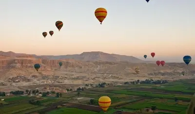 a group of hot air balloons flying over a field at Cleopatra Nile Cruise From Luxor 3&4 Nights Every Saturday and Monday, Thursday in Luxor