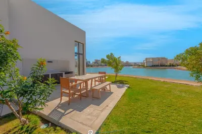 a patio with a table and chairs next to the water at Ascot Bay, Premium 5BR Lagoon Beach House & Pool in Tawila, El Gouna in Hurghada