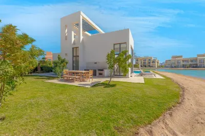 a white house with a picnic table on a lawn at Ascot Bay, Premium 5BR Lagoon Beach House & Pool in Tawila, El Gouna in Hurghada