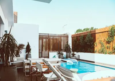 a patio with a swimming pool and white chairs at Peaceful Villa 3BR at Sholan with Private Heated Pool in Hurghada