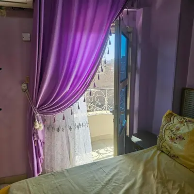 a bedroom with a purple curtain and a window at Susan's Guest House and Tours in Luxor