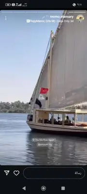 a boat with a flag on the water at NUBIAN MONALIZA guest house in Aswan