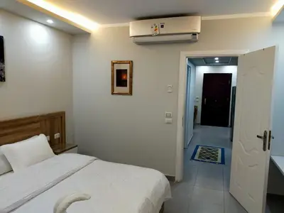 a bedroom with a white bed and a hallway at Happy Home in Hurghada