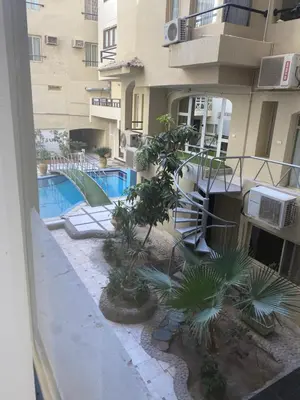an apartment building with a swimming pool and palm trees at Beautiful apartment near sea 1+1 Dream Beach in Hurghada