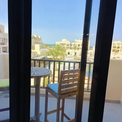 a room with a balcony with a table and a chair at Nayah Stays, Luxurious bedroom in Fanadir Marina in Hurghada