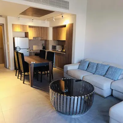 a living room with a couch and a table and a kitchen at Nayah Stays, Luxurious bedroom in Fanadir Marina in Hurghada