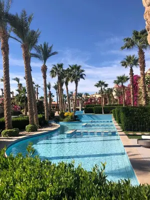 a swimming pool with palm trees in a resort at Penthouse in Hurghada