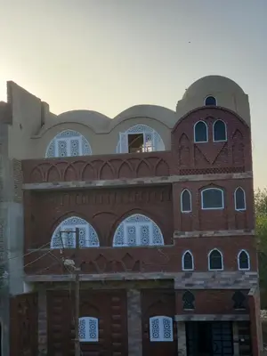 a red brick building with white windows on it at Laila Flat in Al Aqālitah