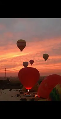 a group of hot air balloons in front of a sunset at Laila Flat in Al Aqālitah