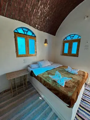 a bedroom with a bed and two windows at Nubian King in Aswan
