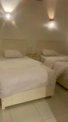 two beds in a room with white sheets and lights at Moon House of Luxor in Luxor