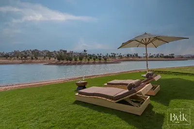 two lounge chairs and an umbrella next to the water at BYTK - La Galería in Hurghada