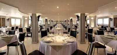 a banquet hall with white tables and black chairs at Cleopatra Nile Cruise in Luxor
